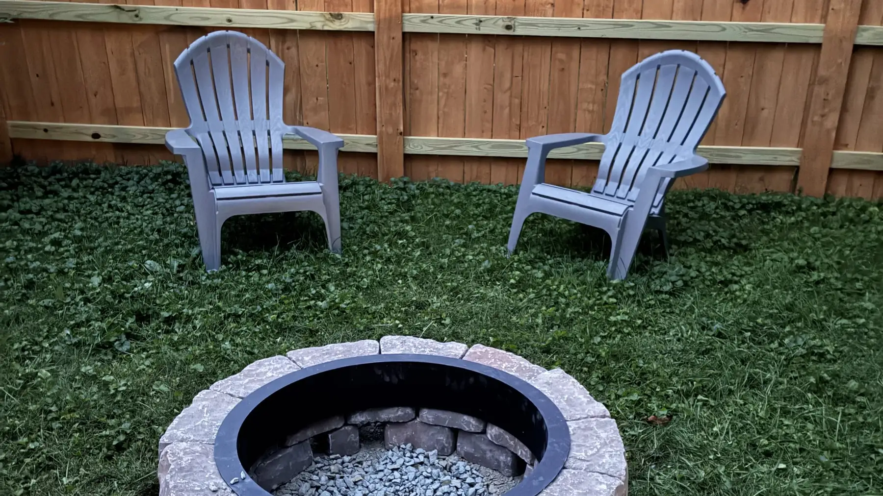 Backyard fire pit and seating area beside a Star City Fence Co wood fence