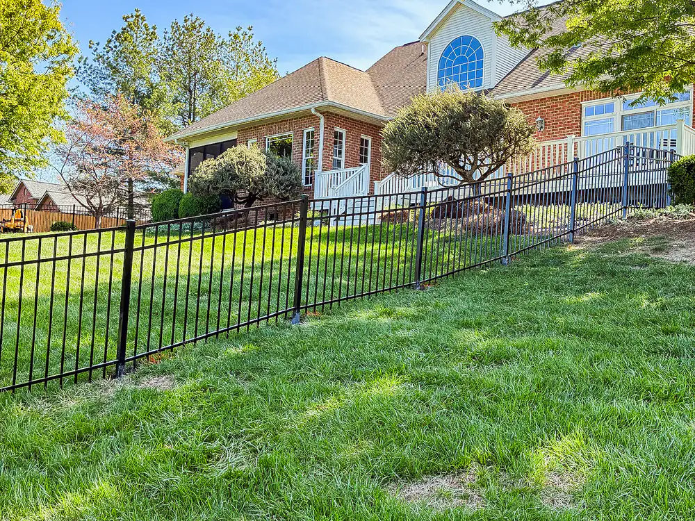 Black aluminum estate fence along the front lawn of a brick home installed by Star City Fence Co