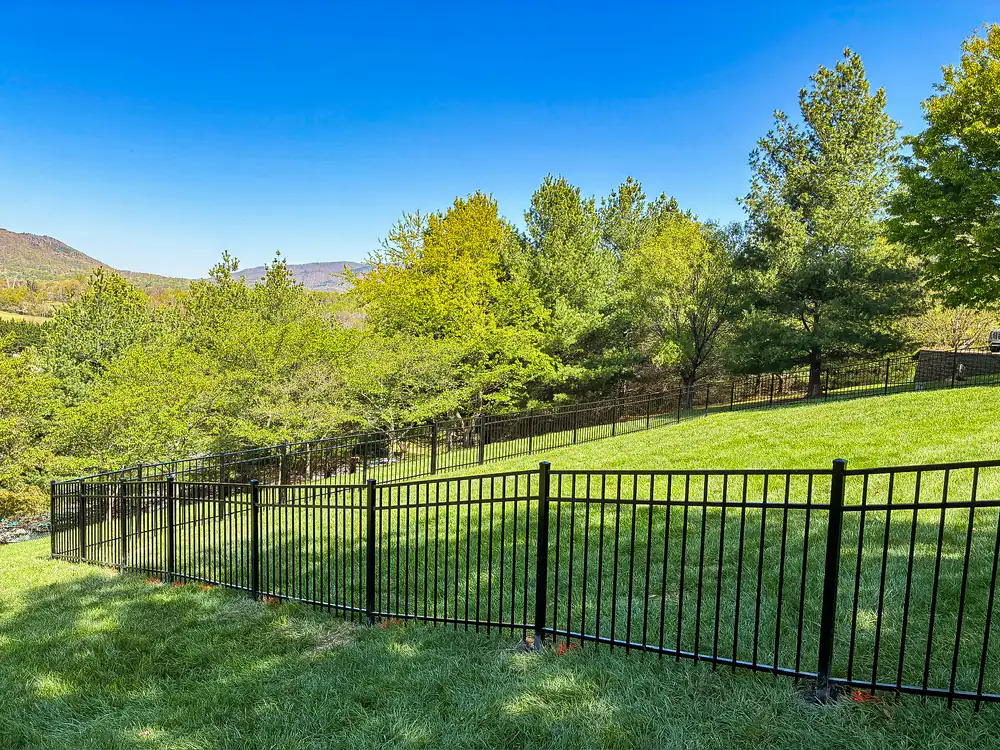 Black aluminum fence enclosing a lawn with the Blue Ridge mountains behind it