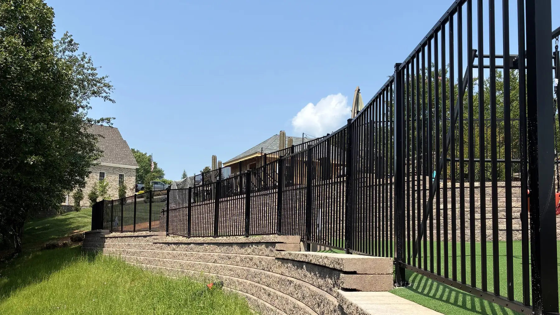 Black aluminum fence installed along a curved retaining wall in Roanoke