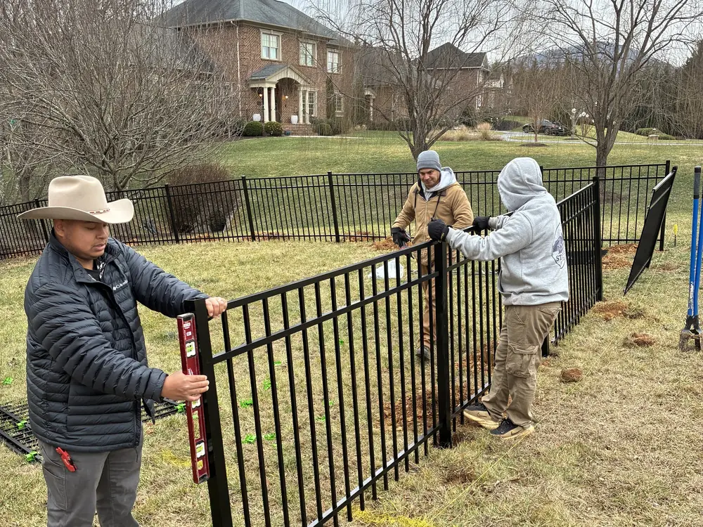 Star City Fence Co crew leveling a black aluminum fence post during installation