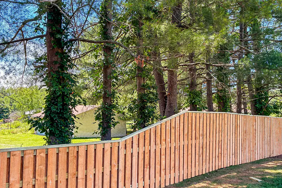 Wood privacy fence running through a wooded pine yard in Roanoke