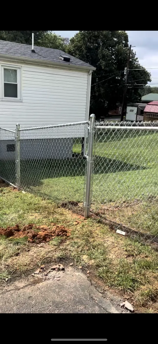 Chain link gate post repaired and reset beside a home
