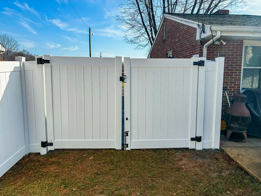 White vinyl privacy fence with a double swing gate in a Roanoke backyard