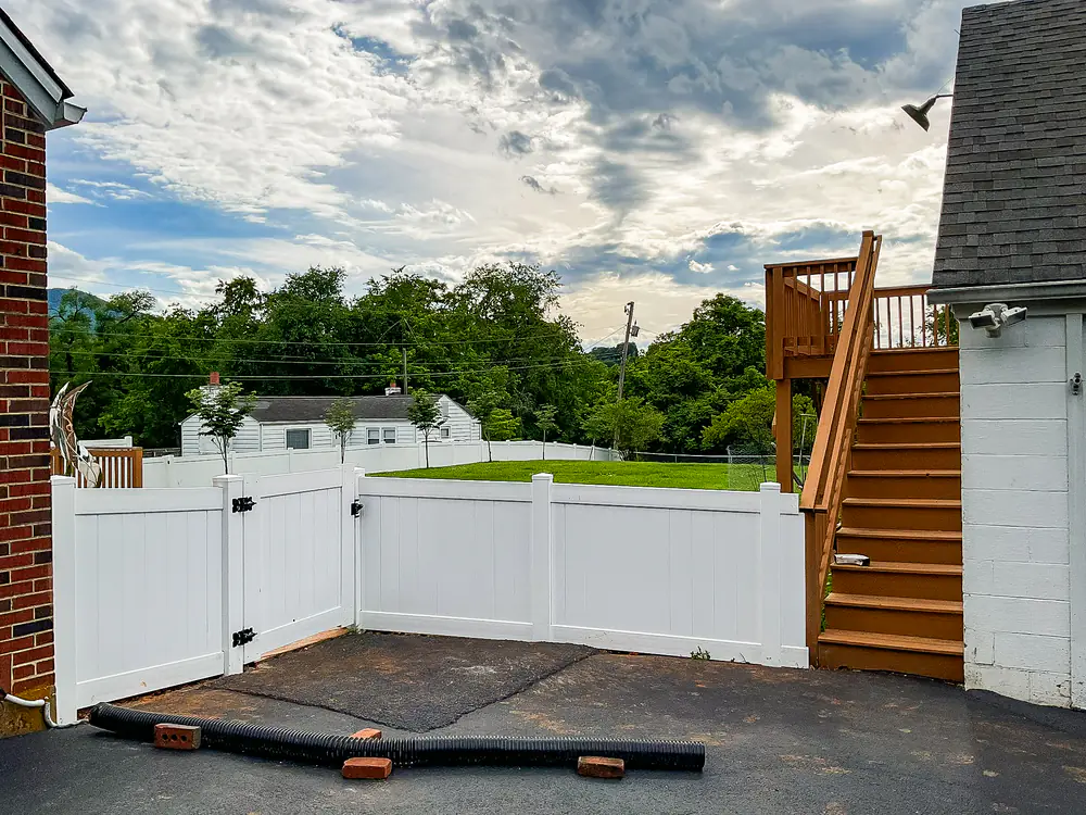 White vinyl privacy fence and double gate enclosing a patio in Roanoke