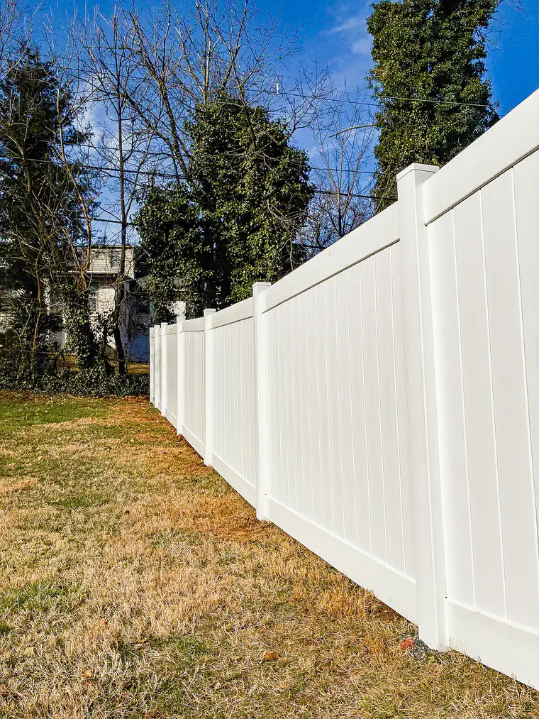 White vinyl privacy fence running along a shaded side yard in Roanoke