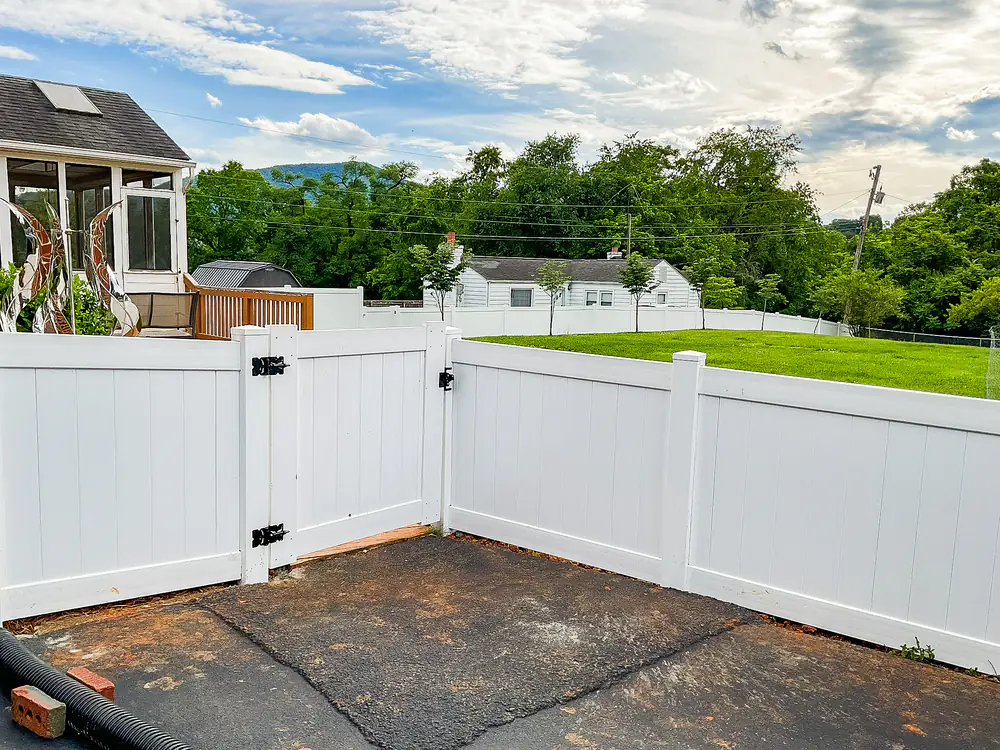 White vinyl privacy fence with double gate opening onto a patio in Roanoke