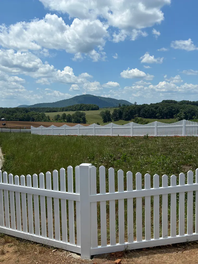 Scalloped white vinyl picket fence with the Blue Ridge mountains behind it in Roanoke