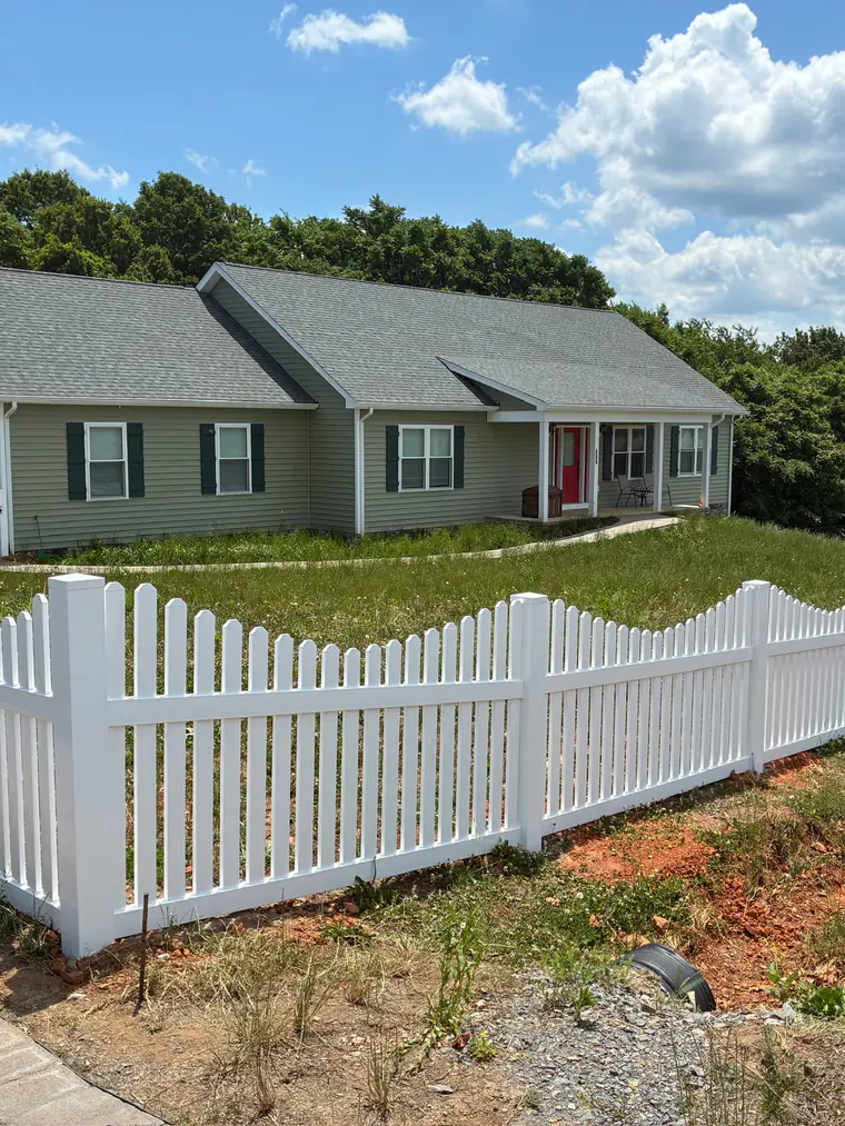 Scalloped white vinyl picket fence around the front yard of a Roanoke home