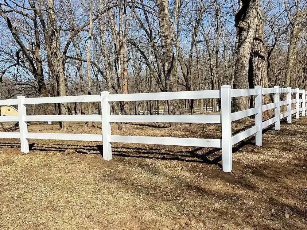 White vinyl ranch rail fence on a wooded property