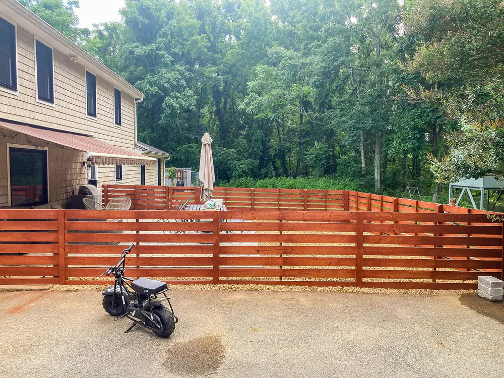 Stained horizontal-plank wood fence along a driveway in Roanoke