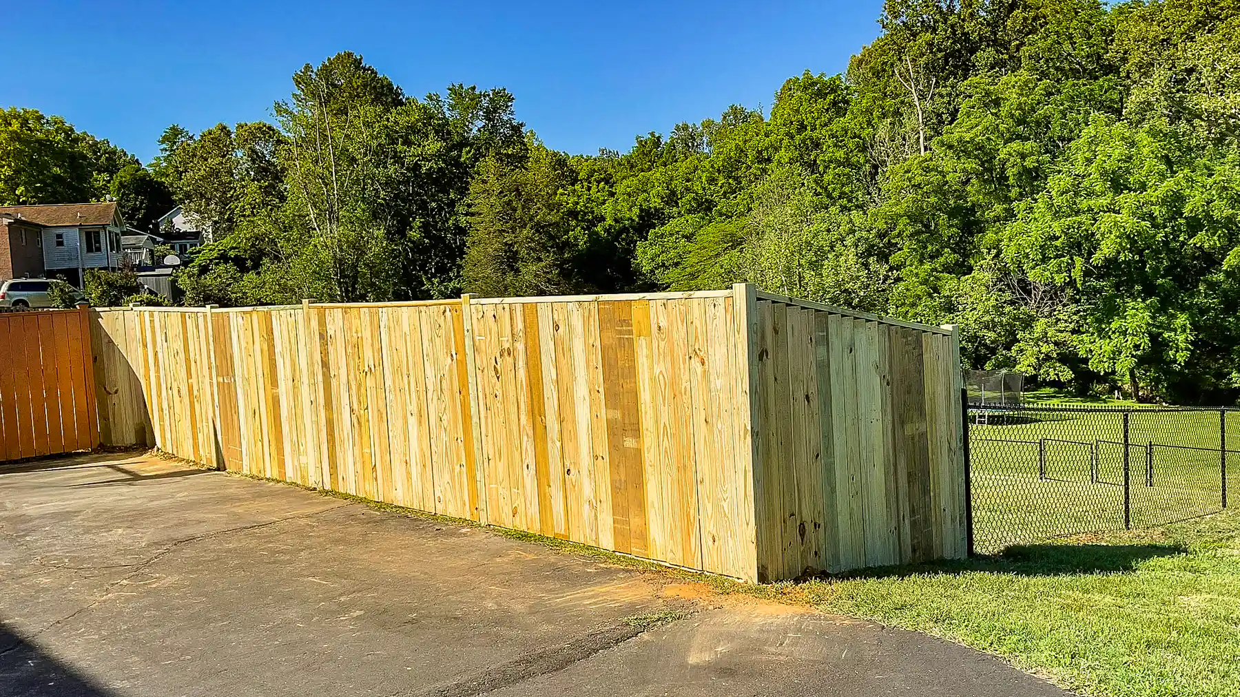 Fresh wood privacy fence along a driveway under a blue sky in Roanoke